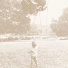 In the photo Archie is standing with his back to the camera holding a large bunch of balloons.