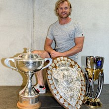 Scott Robertson poses with the Mitre 10 Cup, the Ranfurly Shield and the Super Rugby trophy in 2017.