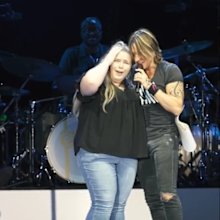 Keith Urban with fan on stage.