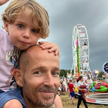 jonnie irwin holding his son on his shoulders at a carnival
