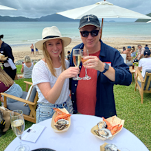 Guests of Qantas' Hamilton Island Mystery Flight relax with Champagne on the beach-facing lawn.