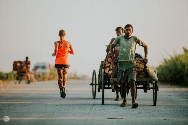 Samantha Gash running past a man pulling a rickshaw in India.