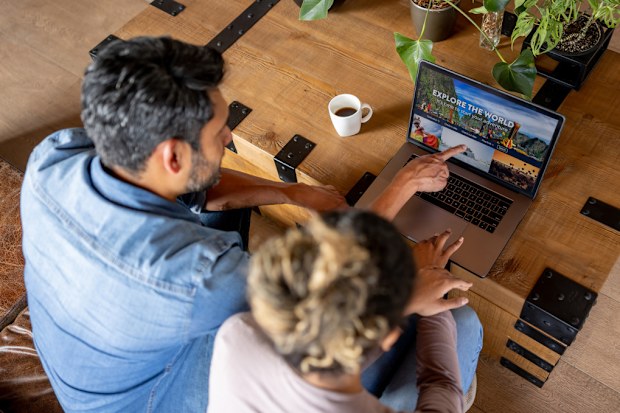 Happy couple at home booking a trip online using their laptop computer