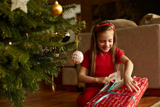 Child unwrapping Christmas gift