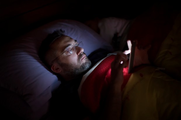 Man on phone in bed at night
