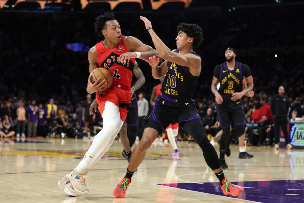 Scottie Barnes of the Raptors dribbles into the defence of Max Christie of the Lakers.