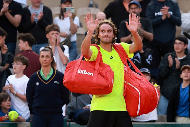 Stefanos Tsitsipas of Greece applauds fans as he walks off court after his defeat to Matteo Gigante of Italy.