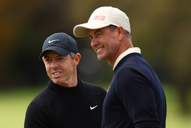 Rory McIlroy (L) speaks with Adam Scott (R) during practice prior to the Crown Australian Open 2025.