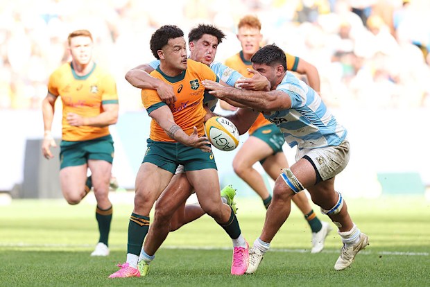 Hunter Paisami of the Wallabies offloads the ball whilst being tackled.