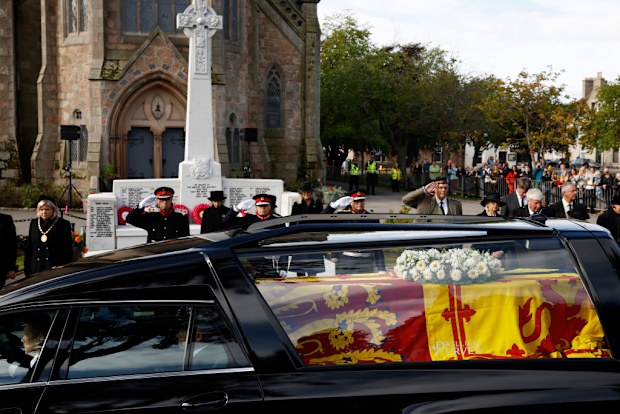 BALLATER, ABERDEENSHIRE - SEPTEMBER 11: People gather in tribute as the cortege carrying the coffin of the late Queen Elizabeth II passes by on September 11, 2022 in Ballater, United Kingdom. Elizabeth Alexandra Mary Windsor was born in Bruton Street, Mayfair, London on 21 April 1926. She married Prince Philip in 1947 and ascended the throne of the United Kingdom and Commonwealth on 6 February 1952 after the death of her Father, King George VI. Queen Elizabeth II died at Balmoral Castle in Scotl