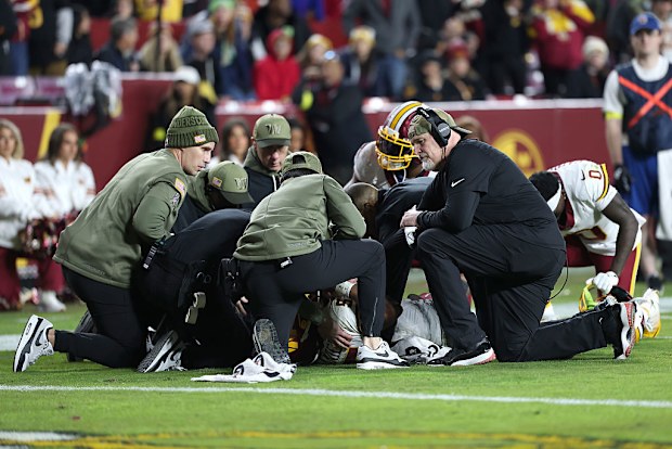 Jayden Daniels #5 de los Comandantes de Washington es examinado por personal médico después de resultar herido.