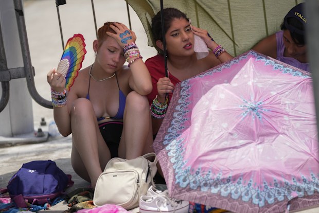 Taylor Swift fans wait for the doors of Nilton Santos Olympic stadium to open for her Eras Tour concert amid a heat wave in Rio de Janeiro, Brazil, Saturday, Nov. 18, 2023. A 23-year-old Taylor Swift fan died at the singer's Eras Tour concert in Rio de Janeiro Friday night, according to a statement from the show's organizers in Brazil.   (AP Photo/Silvia Izquierdo)