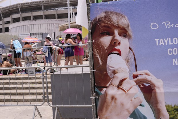 Taylor Swift fans wait for the doors of Nilton Santos Olympic stadium to open for her Eras Tour concert amid a heat wave in Rio de Janeiro, Brazil, Saturday, Nov. 18, 2023. A 23-year-old Taylor Swift fan died at the singer's Eras Tour concert in Rio de Janeiro Friday night, according to a statement from the show's organizers in Brazil.  (AP Photo/Silvia Izquierdo)