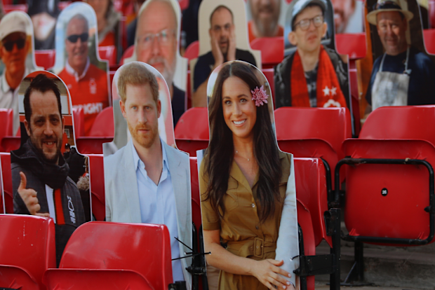 The Duke and Duchess of Sussex appear as cardboard-cut-outs at the football.