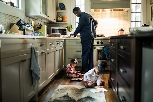 Father cooking breakfast for daughters in kitchen