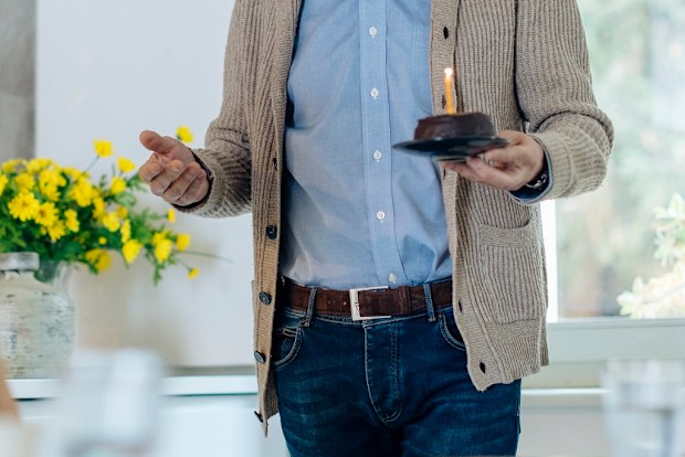 Mature couple celebrating birthday with cake in kitchen at home