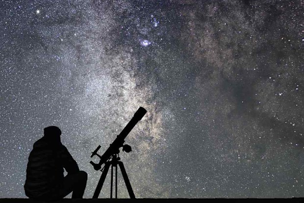 Person looking into space using telescope