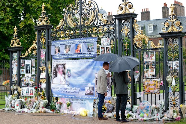 William and Harry view tributes to Diana, Princess of Wales left at the gates of Kensington Palace after visiting the Sunken Garden on August 30, 2017.