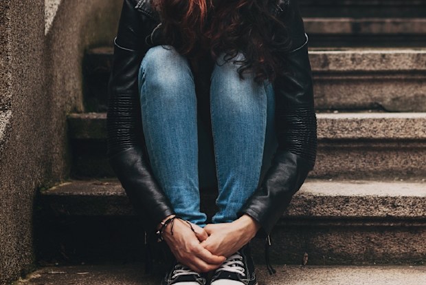 Lonely teenager sitting on stairs with copy space