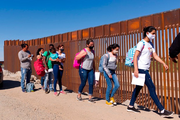 A group of Brazilian migrants walk around a gap in the US-Mexico border in Yuma, Arizona, seeking asylum in the United States after crossing over from Mexico in June 2021.
