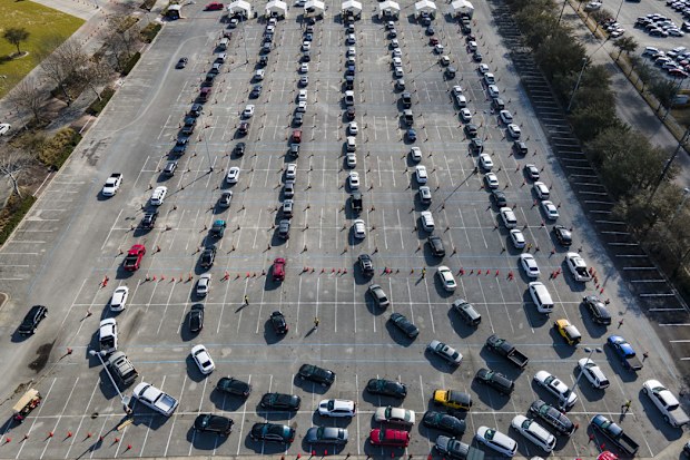 Cars line up in a parking lot at NRG Park as people wait to receive a COVID-19 vaccine at a federally supported supersite at the Harris County facility, Wednesday, Feb. 24, 2021, in Houston
