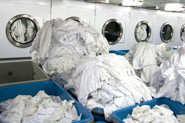 white sheets in large piles ready to be washed or dried in industrial sized machines