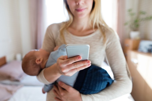 Mum holding her baby and texting someone