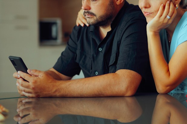 Carefree husband and wife browsing the internet to buy something couple looking at phone