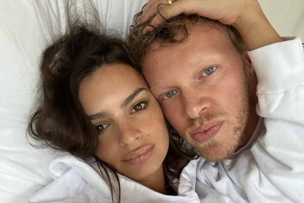 Emily Ratajowski and her husband Sebastian Bear-McClard lying in bed.