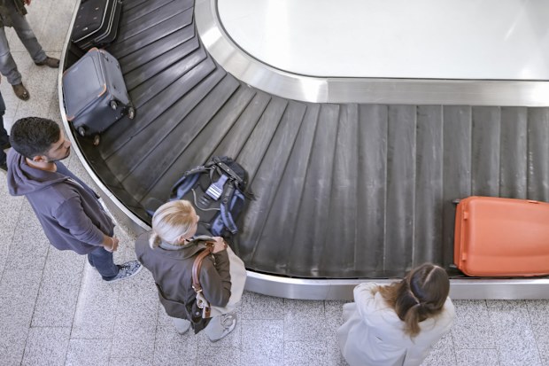 Elevated view of business people standing at baggage claim in airport.