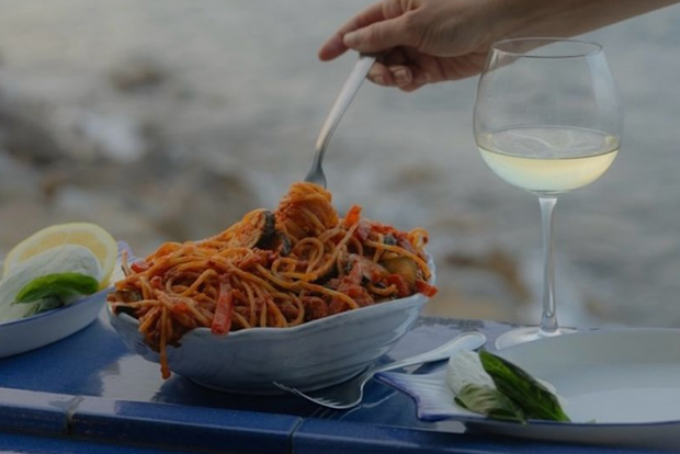 A plate of pasta being eaten with wine.