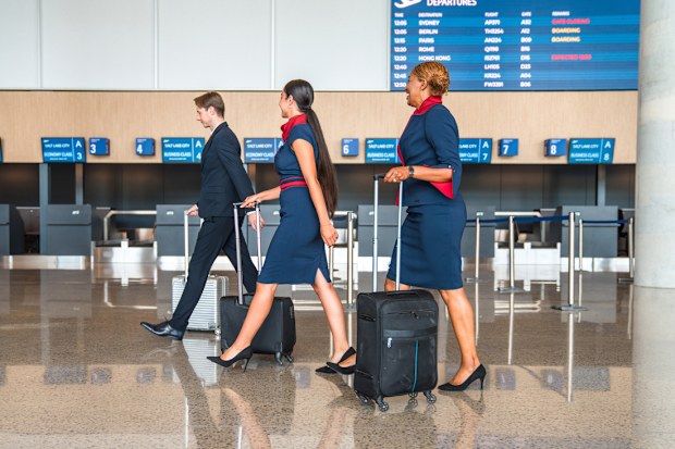 Diverse air crew walking through the airport lobby dragging their personal luggage. On their way to the airplane and get ready to work.