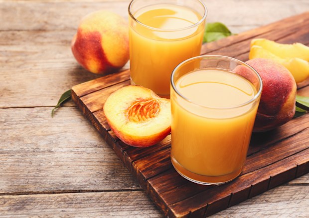 Natural peach juice and fresh fruits on wooden table. 