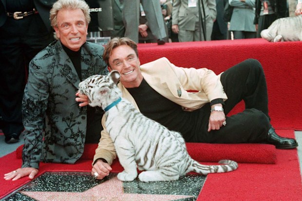 Illusionists Siegfried Fischbacher, left and Roy Uwe Ludwig Horn pose for photographers with a white tiger cub after they unveiled their star on the Hollywood Walk of Fame in Los Angeles, Calif., on Sept. 23, 1994