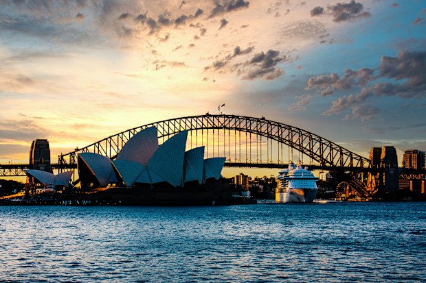 Color Photograph of the Sydney Opera House and Sydney Harbor Bridge at sunset with a cruise ship leaving Circular Quay