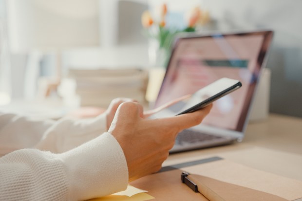 Close-up young lady freelance focus mobile phone chat with colleagues work finance graph account chart market plan in laptop at home. Girl student learn online at house, Work from home concept.