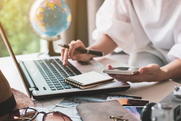 Young traveler planning vacation trip and searching information or booking hotel on laptop, Travel concept
