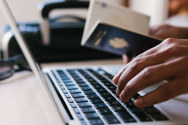 Passport and man on laptop booking vacation, vacation or flight to tropical destination and reading hotel website, concept of Travelling.