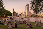 Picnics on Riverside Green in South Bank, a recreational area in Brisbane, Australia, likely host of the 2032 Olympic Games. South Bank looks across the Brisbane River to the city skyline.