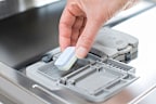Dishwasher tablet being placed into the dispenser.