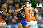 Knights winger Dominic Young attempts to break the tackle of two Wests Tigers defenders.