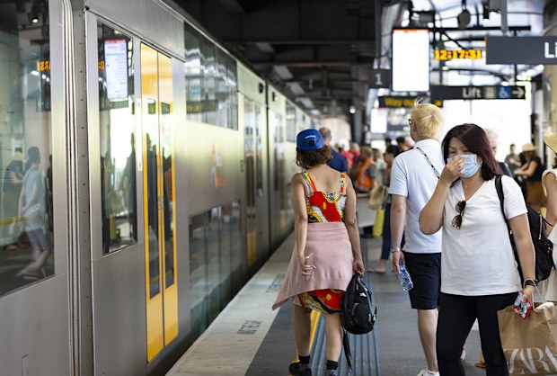 Sydney, Australia - March 01, 2020: Circular Quay, young asian woman wearing face mask and other people waiting to board train at Circular Quay train station