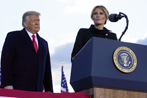 President Donald Trump listens as First Lady Melania Trump speaks before boarding Air Force One at Andrews Air Force Base, Md., Wednesday, Jan. 20, 2021.