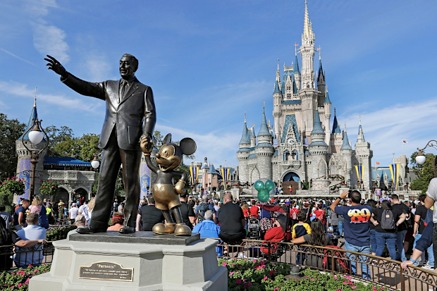 FILE - In this Jan. 9, 2019 photo, guests watch a show near a statue of Walt Disney and Micky Mouse in front of the Cinderella Castle at the Magic Kingdom at Walt Disney World in Lake Buena Vista, part of the Orlando area in Fla.  (AP Photo/John Raoux, File)