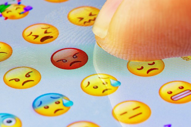 Finger touching emojis on screen.