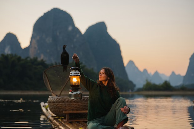 Serene woman exploring traditional wooden rafts in Xingping, Guilin, China at sunset