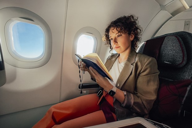 A focused Caucasian female relaxing while being on a plane.