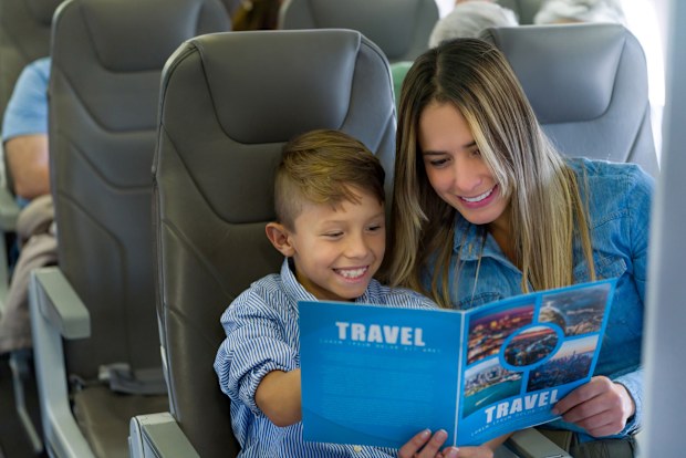 Portrait of a happy mother and son traveling by plane and reading a travel guide - lifestyle concepts