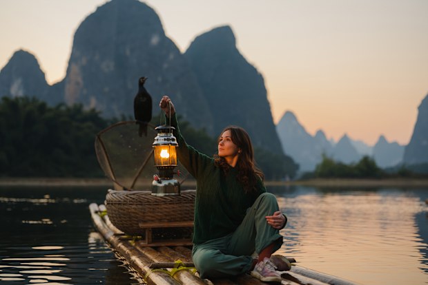 Serene woman exploring traditional wooden rafts in Xingping, Guilin, China at sunset