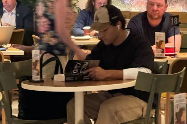 Actor Josh Heuston reading Onyx Storm at Sydney airport